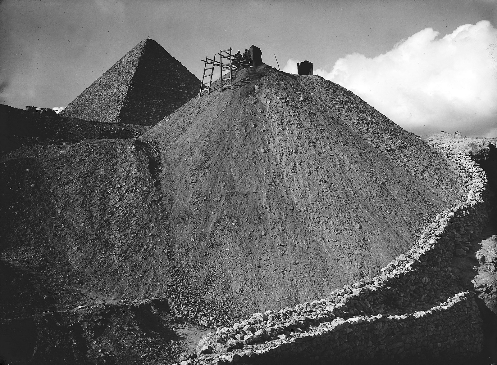 In January 1930 Ibrahim photographed an excavation mound at Giza with the Great Pyramid of Khufu peering from behind, rising only slightly taller in the frame, juxtaposing past and present. By this time Ibrahim’s two decades of experience behind the lens showed in his articulate visual storytelling through composition and association, as well as dramatic contrasts of light and shadow, and in his expert control of the tonal ranges within images that he produced in the field camp’s darkroom.
