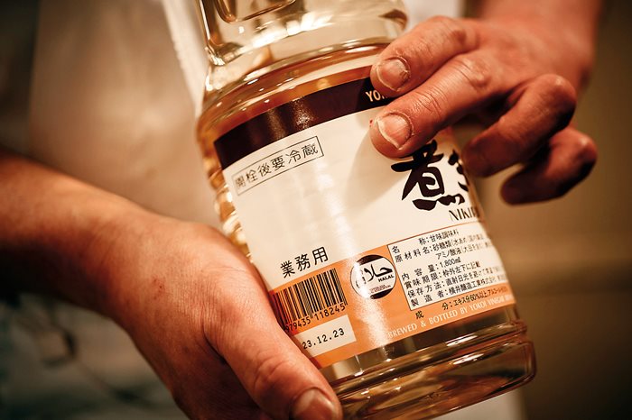 Chef Toshihiro Maki shows the circular halal mark on a jar of alcohol-free vinegar that he uses in his dishes. Grocery stores supplying halal products are opening all across Tokyo, including, middle, in the lively Shin-Okubo district. 