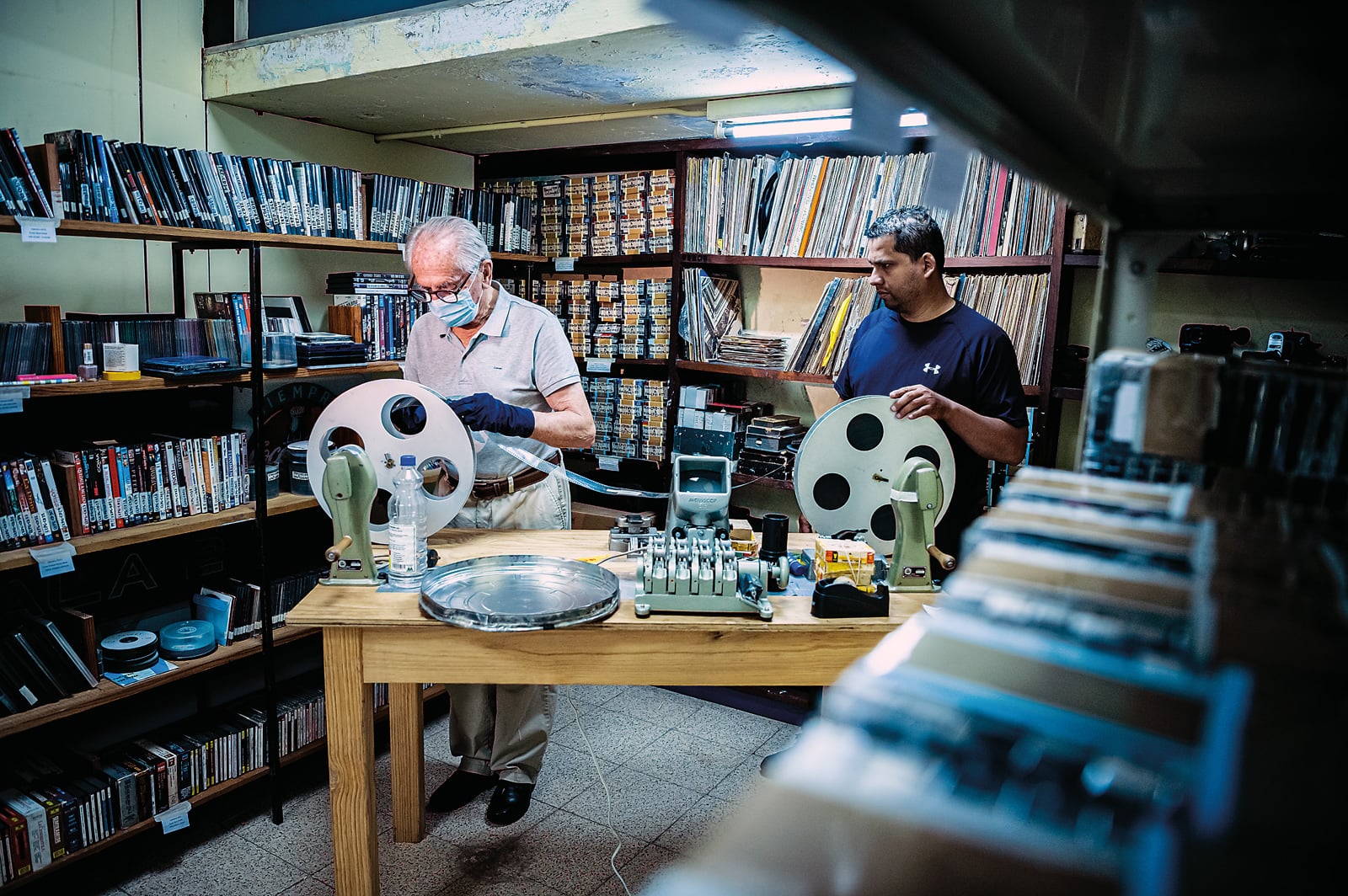 Kafati’s old friend Rene Pauk, left, and archival technician Marxis Lenin Hernández inspect a copy of Kafati’s masterpiece, No hay tierra sin dueño (There Is No Land Without an Owner), at the Cinemateca Enrique Ponce Garay. Pauk and the film archive’s manager, Luis Griffin, are personally overseeing the restoration of Kafati’s films.